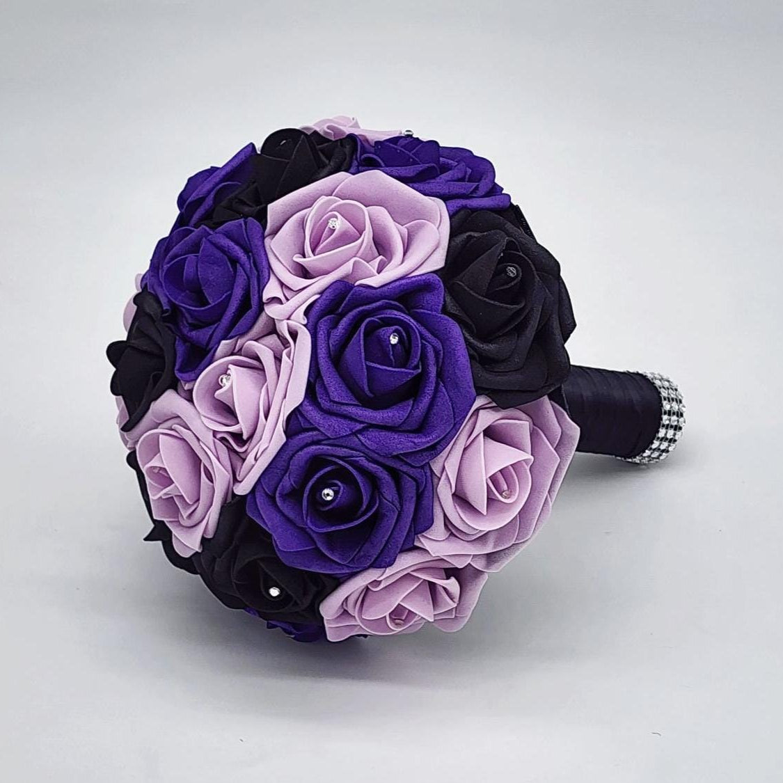 purple, lilac, and black real touch rose bouquet with satin black ribbon and finished with silver bling wrap. Rhinestones are placed on every rose.