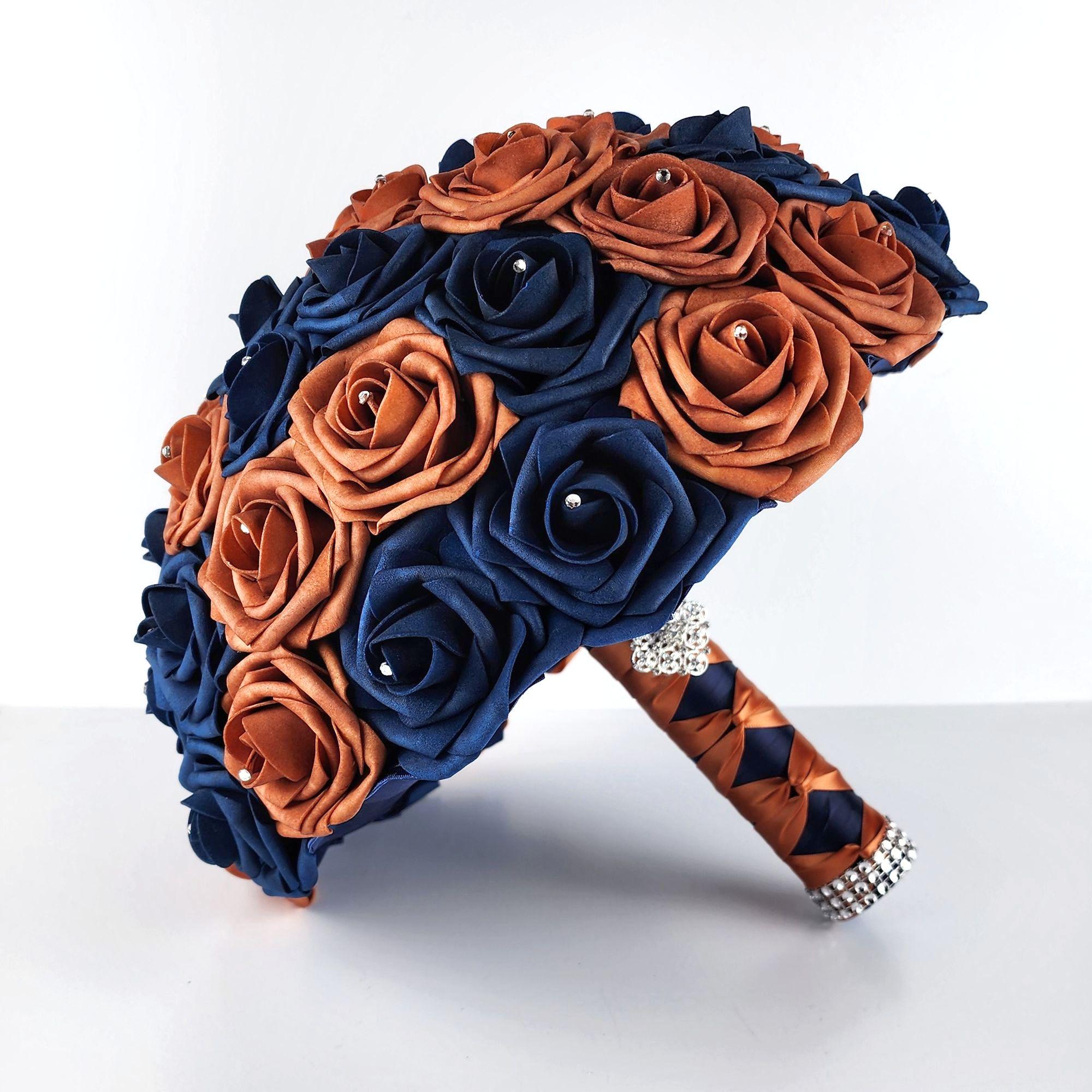 Burnt orange and navy rose wedding bouquet with rhinestones in every rose. Handle is made up of burnt orange and navy ribbon in a French twist and finished with silver brooch and bling wrap.