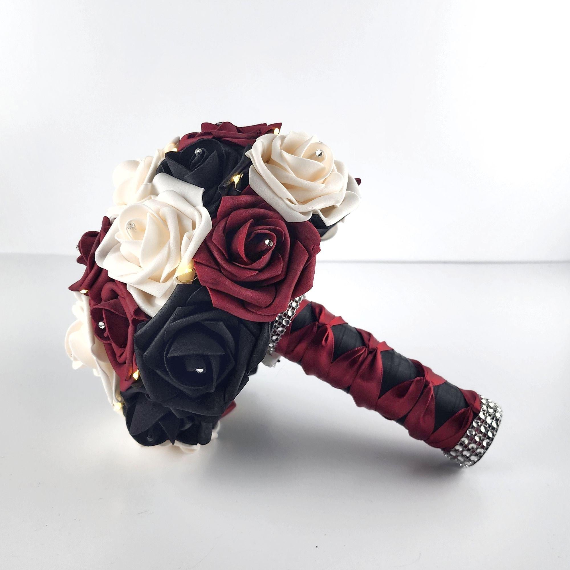 Black, Burgundy, and Cream Fairylight bouquet- Wedding bouquet-Bouquet is made using real touch roses. Handle is Blackwith a Burgundy French twist and finished with silver bling wrap. Fairy Lightsare strung through bouquet