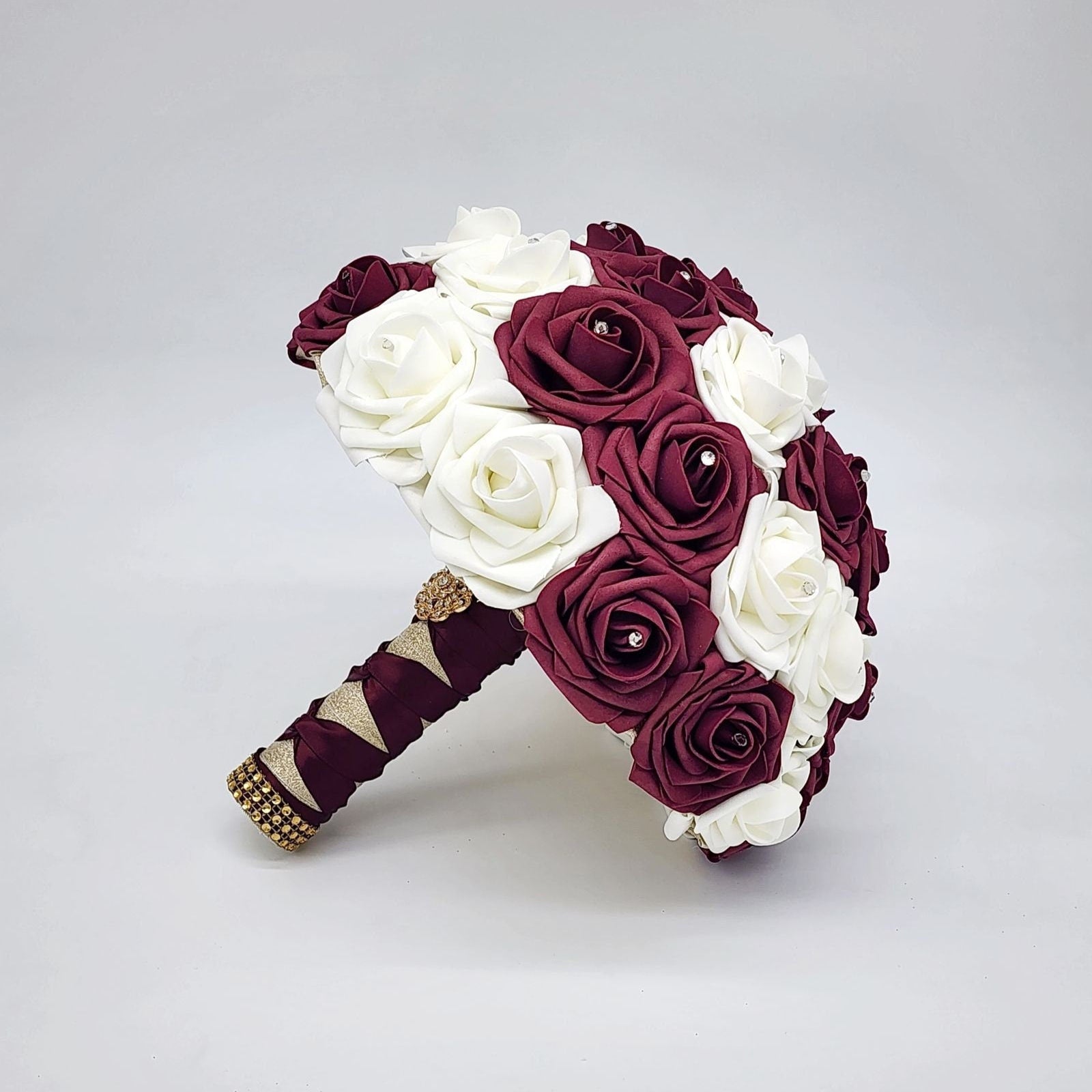 Burgundy and cream bouquet with gold and burgundy handle. Gold brooch and bling wrap