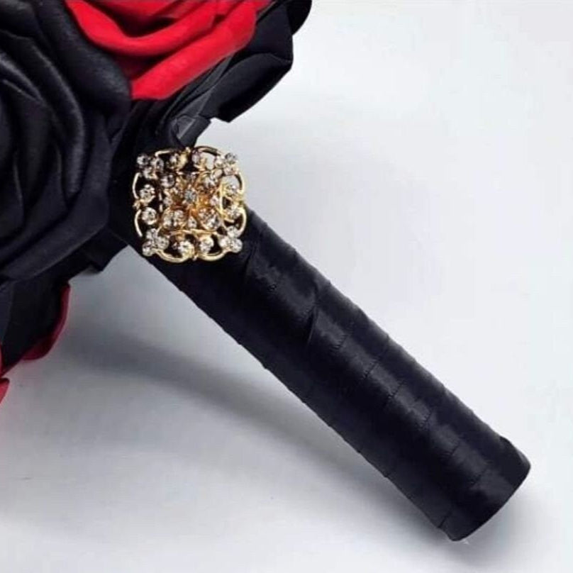 Black satin ribbon handle finished with a gold brooch.