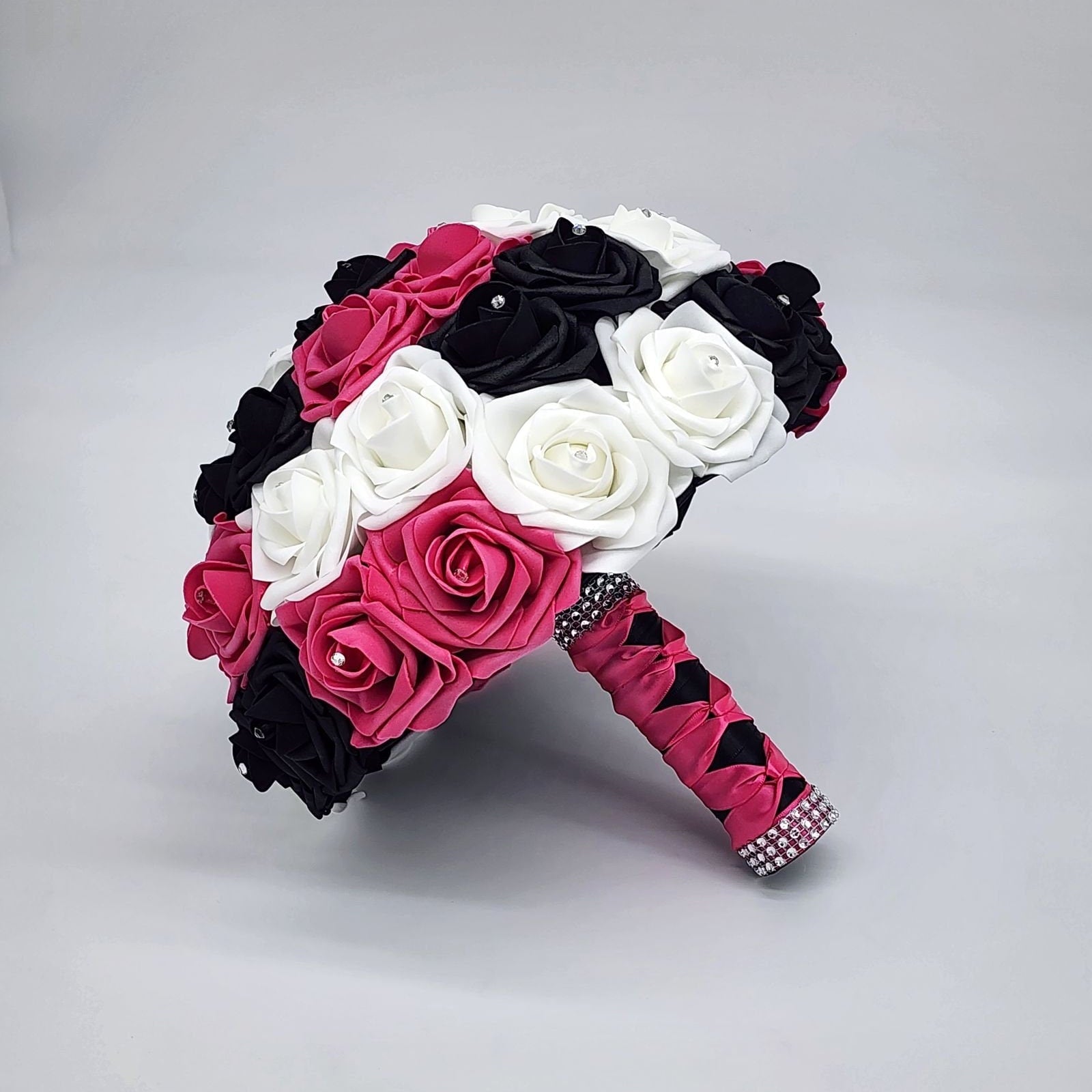 Hot pink, black, and white bouquet with rhinestones on every rose. Handle is made out of hot pink and black satin ribbon in a French twist and ends with silver bling wrap.