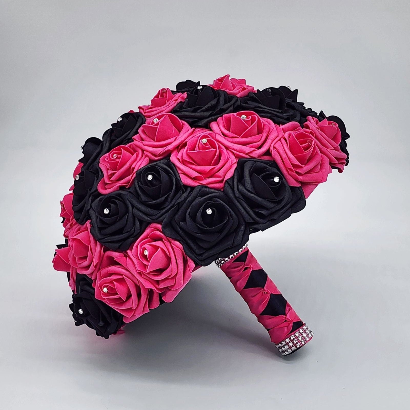 Hot pink and black rose bouquet with rhinestones on every rose. handle is made up of hot pink and black satin ribbon in a French twist style and finished with silver bling wrap.