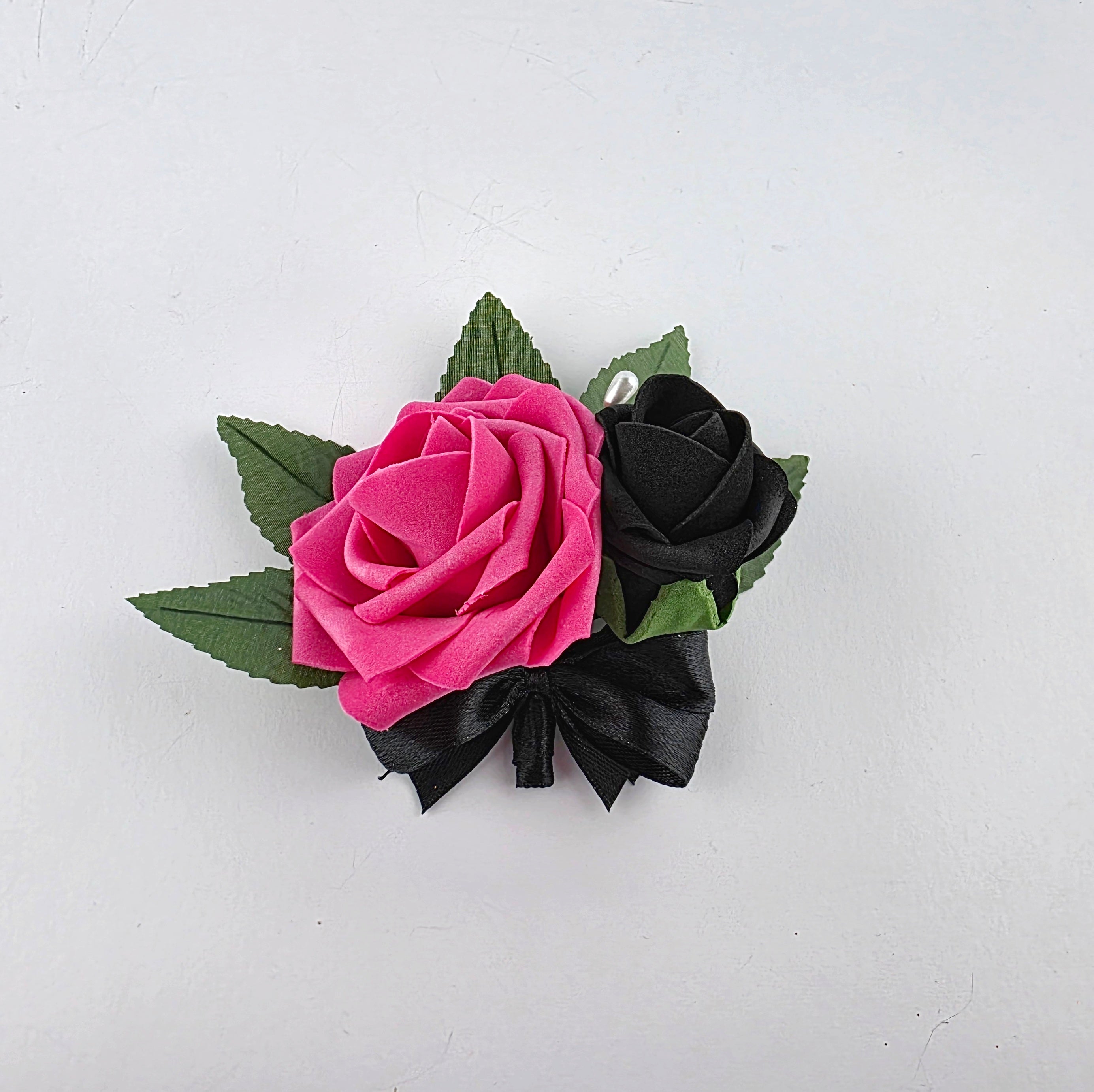 Hot pink and black pin on corsage and boutonniere with 5 green leaves and pearl pin