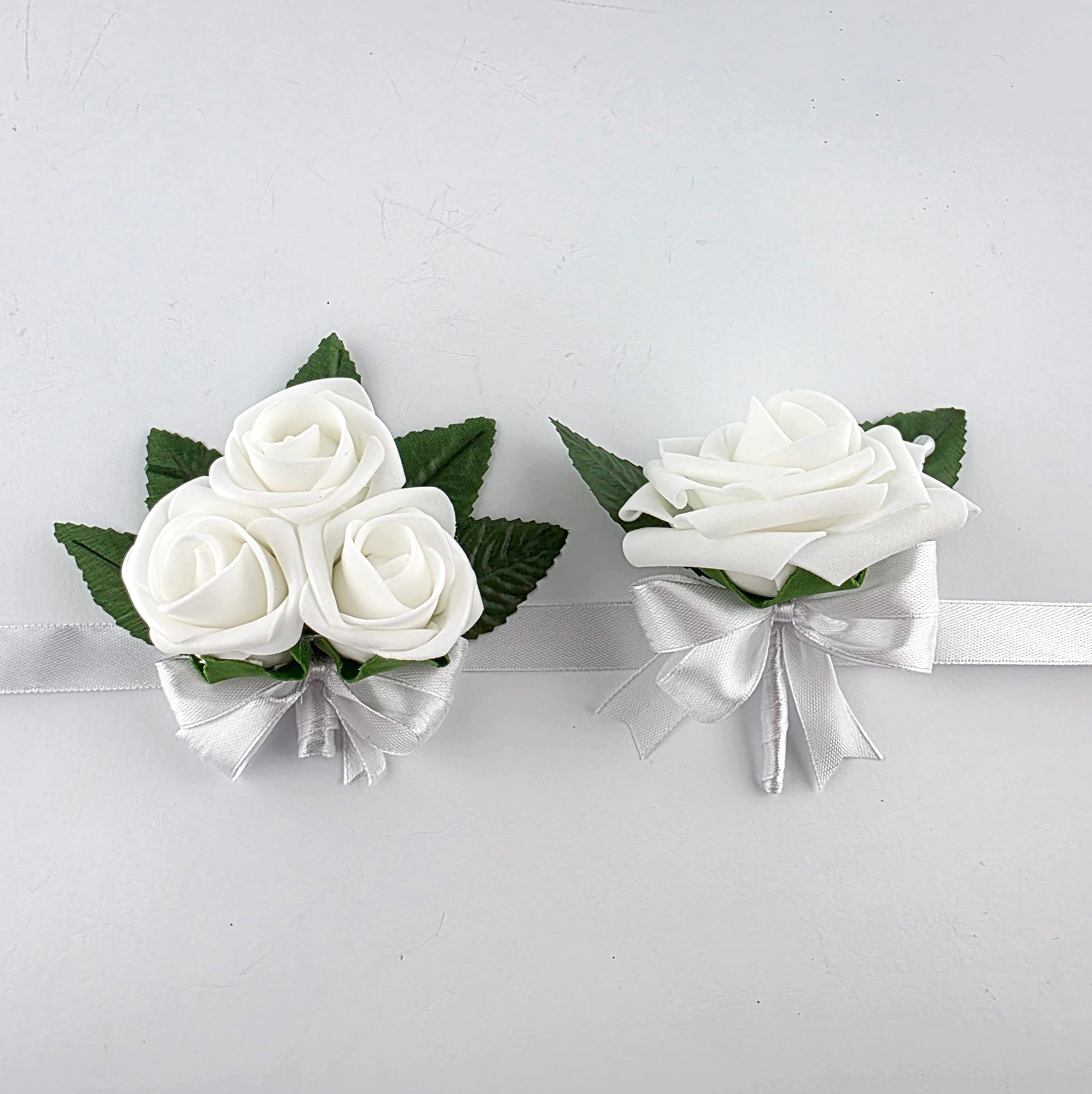 Pair of white wrist corsage and white boutonniere