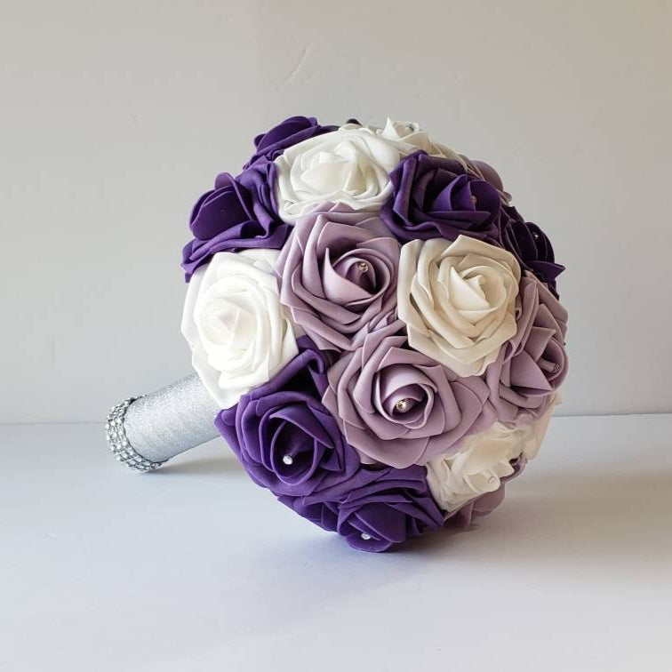 lilac, purple, and white bridal bouquet made with real touch roses. rhinestones are in the center of every rose. Handle is made with silver ribbon and finished with silver bling wrap.