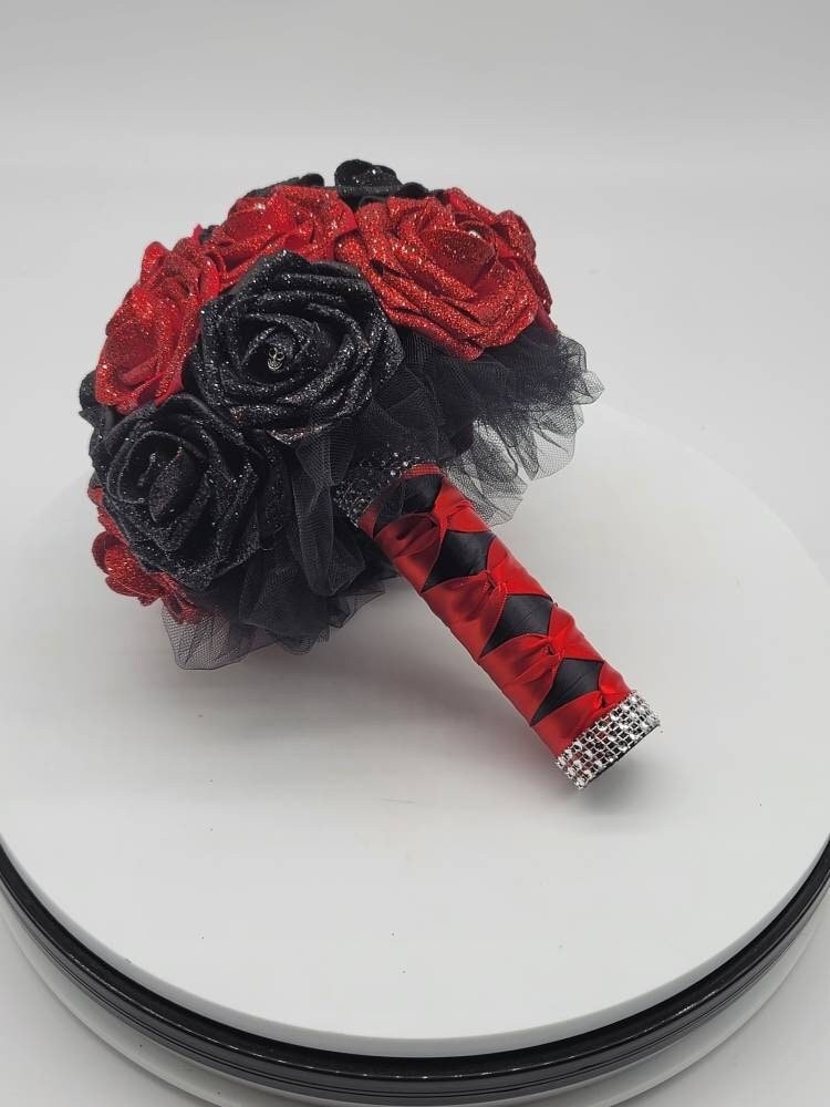 Red and black glitter roses with silver skulls on every rose. Handle is made up of black tulle and satin red and black ribbon in a French twist style. Finished with silver bling wrap