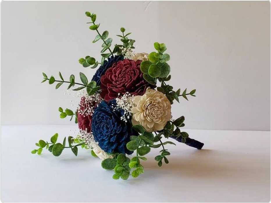 Burgundy, Navy, and White Sola wood bridal bouquet with eucalyptus greenery and baby&#39;s breath. Handle is wrapped in navy blue satin ribbon.